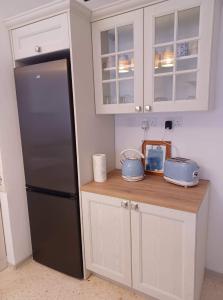 a kitchen with a black refrigerator and white cabinets at Lucky Summer Marsalforn Holiday Apartment in Marsalforn