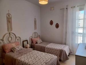 a bedroom with two beds and a window at Lucky Summer Marsalforn Holiday Apartment in Marsalforn