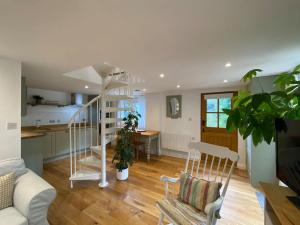 a living room with a spiral staircase and a kitchen at Candlewick Cottage in Steeple Aston