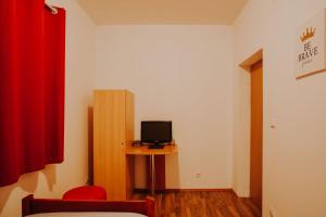 a room with a small television on a table with a red curtain at Sobe Anita in Vukovar