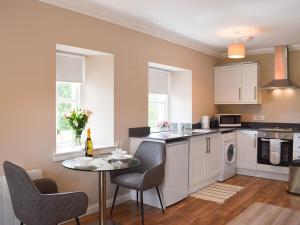 una cucina con tavolo e sedie e una cucina con lavandino di Fascadail-uk34219 ad Aberfoyle