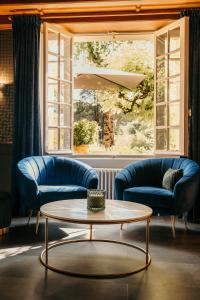 a living room with two blue couches and a table at Hôtel Le Cro-Magnon in Les Eyzies-de-Tayac