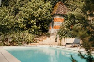 a chair sitting next to a swimming pool at Le Cro-Magnon - hôtel - piscine - climatisation in Les Eyzies-de-Tayac