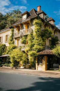 a large building with trees on the side of the street at Le Cro-Magnon - hôtel - piscine - climatisation in Les Eyzies-de-Tayac