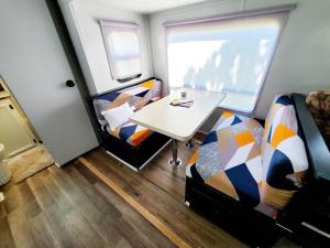 ドーバーにあるWildwood Camper De Sleeps 6-7,のベッド2台とテーブルが備わる小さな客室です。