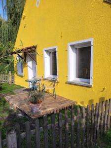 a yellow house with a table and chairs on a wooden deck at Haus Evelynchen Apartment 1 Deutschhof 