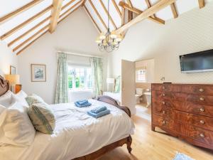 a bedroom with a bed with a dresser and a tv at Pinley Hill House in Shrewley