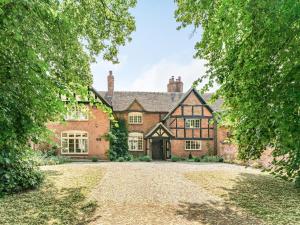 an exterior view of a large brick house with a driveway at Pinley Hill House in Shrewley