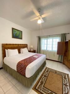 1 dormitorio con 1 cama grande y ventilador de techo en All Nations Guest House en Port Antonio