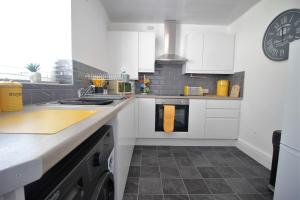 una cucina con armadi bianchi e piano di lavoro di Tower View House - 4 Bedroom - Newly Refurbished - 2 Mins walk to Beach a Blackpool