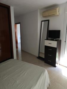 a bedroom with a bed and a flat screen tv at Apartamento 60 m2 en la playa in Torre de Benagalbón