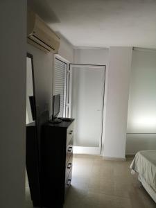 a bedroom with a bed and a dresser with a television at Apartamento 60 m2 en la playa in Torre de Benagalbón