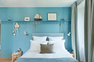 1 dormitorio azul con 1 cama con almohadas blancas en Les Hautes Mers en L'Ile d'Yeu
