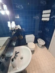 uma casa de banho em azulejos azuis com um lavatório e um WC em Hostal Santa Barbara em Madri