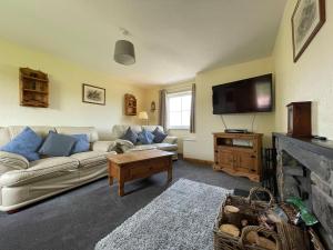 uma sala de estar com um sofá e uma televisão em River Cottage em Forsinain