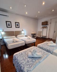 a room with three beds in a room at Hostal Santa Barbara in Madrid