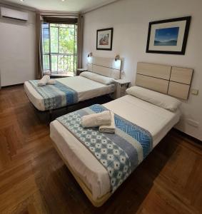 a room with three beds and a window at Hostal Santa Barbara in Madrid