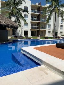 a resort swimming pool with palm trees and a building at ACAPULCO TURQUESA DIAMANTE in Acapulco