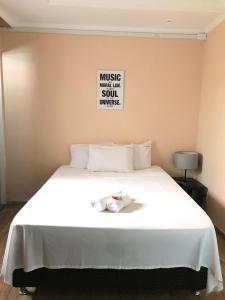 Una cama blanca grande con una toalla. en Pousada Recanto do Arraial do Cabo, en Arraial do Cabo