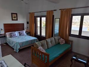 ein Schlafzimmer mit einem Sofa, einem Bett und Fenstern in der Unterkunft InterLaken Apart & Suites in Villa Carlos Paz