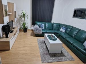 sala de estar con sofá de cuero verde y mesa de centro en Kuća na dan en Šid