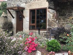 une maison en pierre avec des fleurs devant une fenêtre dans l'établissement A Casiña de Esther, à Teo