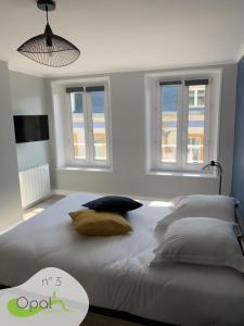a bedroom with a large bed with two windows at OPAL'APPART in Boulogne-sur-Mer