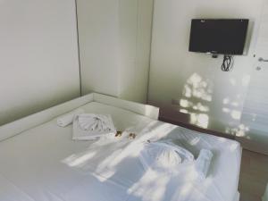 a white bed with two pillows and a tv at Villino Oleandro a pochi passi dalla spiaggia di Simius in Simius