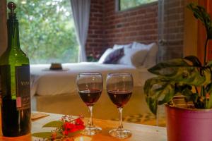 dos copas de vino sentadas en una mesa con una botella de vino en Pacha Eco Lodge Glamping & Hotel en Archidona