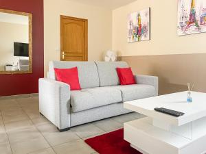 sala de estar con sofá gris y almohadas rojas en Fééria - Appartement au calme proche de Disneyland Paris, en Chessy
