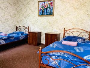 a bedroom with two beds and a painting on the wall at Guest House Evergreen in Margilan