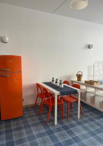 cocina con mesa y 4 sillas rojas en Romantico Monolocale, en Castro di Lecce