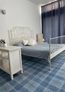 カストロ・ディ・レッチェにあるRomantico Monolocaleのベッドルーム(ベッド1台、白いベビーベッド1台、テーブル付)