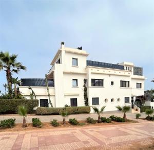 a white building with palm trees in front of it at logis la marine in Sidi Ifni