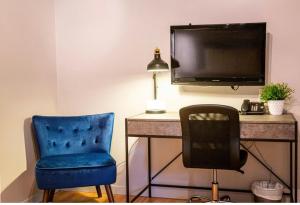 a room with a desk with a tv and a chair at Hotels Hébert in Bécancour