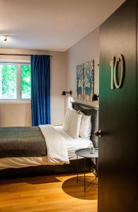 a bedroom with a bed with blue curtains and a table at Hotels Hébert in Bécancour