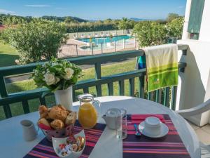 een tafel met eten en sinaasappelsap op een balkon bij Résidence Mer & Golf Ilbarritz in Bidart