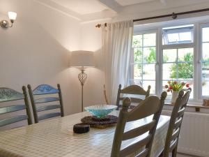 een eetkamer met een tafel, stoelen en ramen bij September Cottage in Chickerell