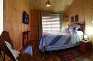 um quarto com uma cama num quarto com paredes de madeira em Bajo la Cruz del Sur - Conguillio em Melipeuco