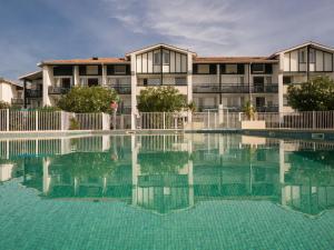 a hotel with a swimming pool in front of a building at Résidence Mer & Golf Ilbarritz in Bidart