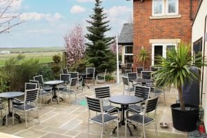 un patio avec des tables et des chaises en face d'un bâtiment dans l'établissement Three Horseshoes Leamside, à Houghton-le-Spring