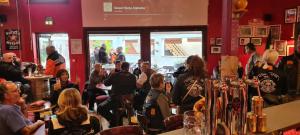 una multitud de personas sentadas en un bar en Cour Du Tonnelier en Bouxwiller
