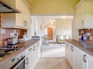 a kitchen with white cabinets and a living room at The Parlour - Uk36122 in Horsington