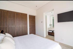 a bedroom with a white bed and a flat screen tv at Amazing Cabo Marina condo with private jacuzzi in Cabo San Lucas