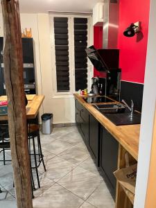 uma cozinha com paredes vermelhas e um balcão de madeira em Le parapluie rouge em Châlons-en-Champagne
