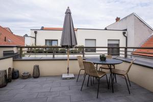 patio con mesa y sombrilla en el balcón en Cesar Apartman, en Sopron