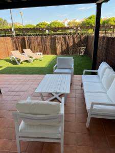 2 sofás blancos y un patio con mesa y sillas. en Jardines de Nuevo Vera - Magnífico Apartamento a Pie de Playa, en Vera