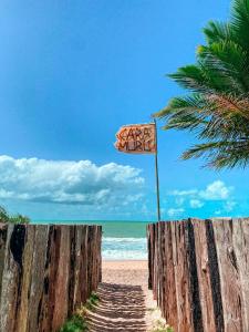 een parasol op het strand naast een houten hek bij Caramuru Hostel Caraíva in Caraíva