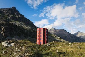 ein rotes Gebäude an der Seite eines Berges in der Unterkunft Hotel Solaria in Bivio