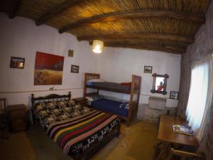 a bedroom with two beds and a wooden ceiling at Casamolle Hostel in Tilcara
